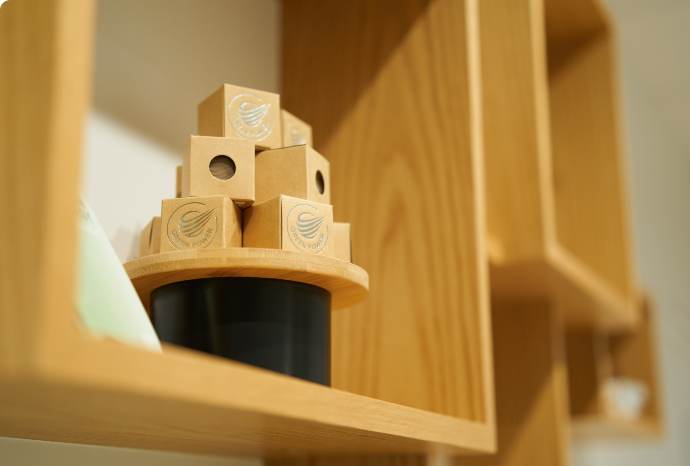 木製棚の上に「GREEN POWER」と書かれたロゴ入りの小箱が円形トレイに積まれている様子